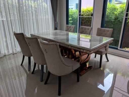 Modern dining area with six upholstered chairs and a large marble table