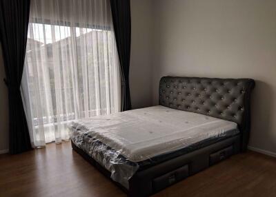 Bedroom with a large bed, headboard, and floor-to-ceiling window with curtains