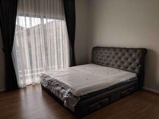 Bedroom with a large bed, headboard, and floor-to-ceiling window with curtains