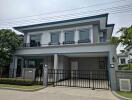 Front view of a modern two-story house with a gated driveway