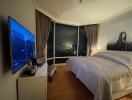 Modern bedroom with large windows showcasing a city night view