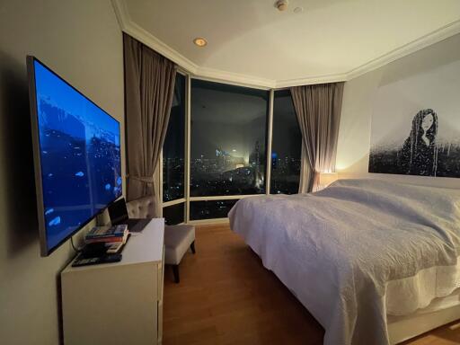 Modern bedroom with large windows showcasing a city night view