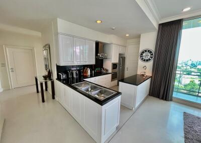 Modern kitchen with white cabinets and island, stainless steel appliances, and a view.