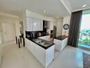 Modern kitchen with white cabinets and island, stainless steel appliances, and a view.