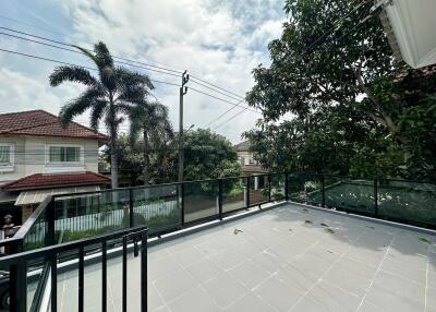 Spacious outdoor terrace with railing and a view of neighboring houses and trees