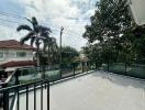 Spacious outdoor terrace with railing and a view of neighboring houses and trees