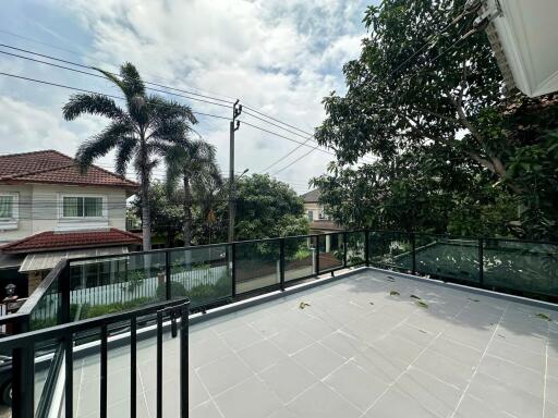 Spacious outdoor terrace with railing and a view of neighboring houses and trees