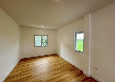 Spacious bedroom with hardwood flooring and two windows