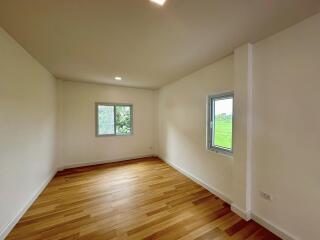 Spacious bedroom with hardwood flooring and two windows