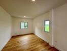 Spacious bedroom with hardwood flooring and two windows