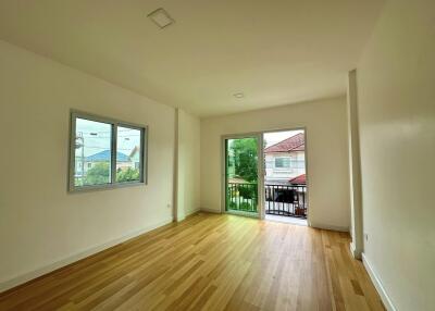 Bedroom with wooden floor, window, and access to balcony