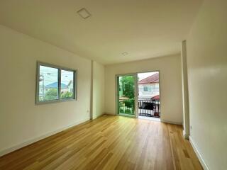 Bedroom with wooden floor, window, and access to balcony