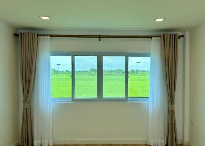 Spacious bedroom with large window and view of greenery