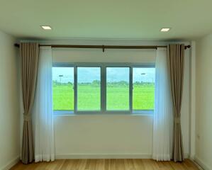 Spacious bedroom with large window and view of greenery