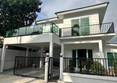 Modern two-story house with large balcony and gated parking area