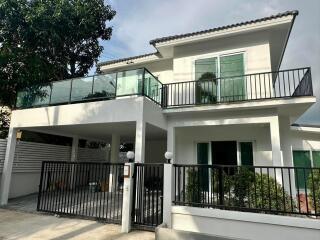 Modern two-story house with large balcony and gated parking area