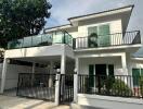 Modern two-story house with large balcony and gated parking area