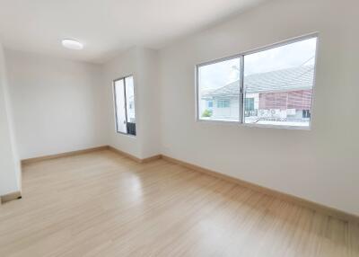 Empty bedroom with wooden floor and large windows