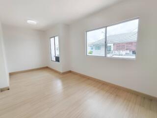 Empty bedroom with wooden floor and large windows