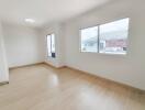 Empty bedroom with wooden floor and large windows