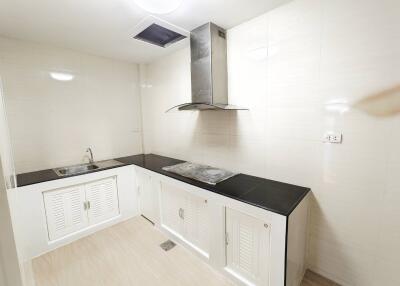 Modern white kitchen with black countertops and stainless steel stove