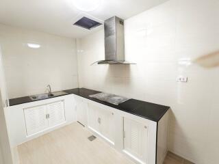 Modern white kitchen with black countertops and stainless steel stove