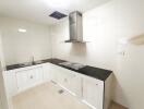 Modern white kitchen with black countertops and stainless steel stove