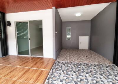 Open area adjacent to a room with sliding glass door, tiled flooring, and wooden ceiling