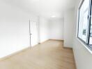 Empty bright room with wooden floor and large window