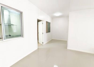 Empty room with white walls and doors, adjacent to kitchen