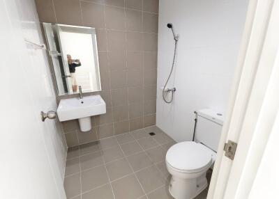 Modern bathroom with tiled walls and floor, including sink, toilet, and shower.