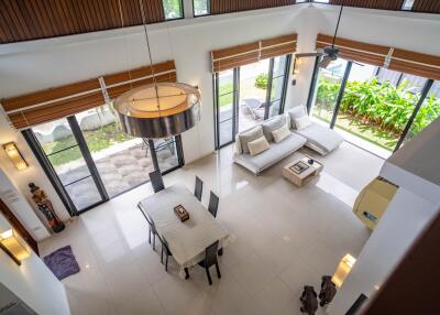 Modern living room with large windows, dining table, and garden view