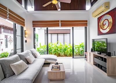 Modern living room with large windows, L-shaped sofa, and television