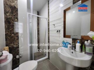 Modern bathroom with shower, sink, mirror, and tiled walls