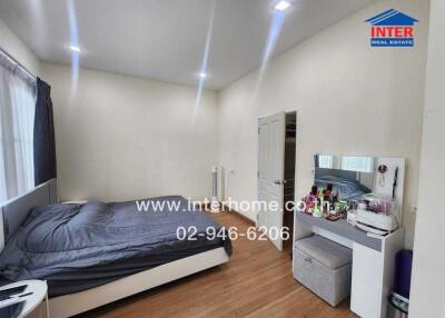 Modern bedroom with a double bed, makeup table, and wooden flooring