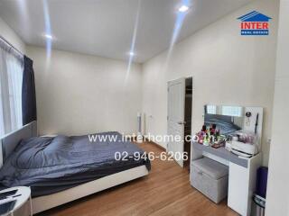 Modern bedroom with a double bed, makeup table, and wooden flooring