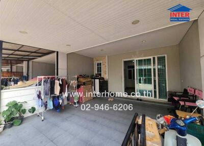 Covered outdoor area of a building with laundry, plants, and a sliding patio door