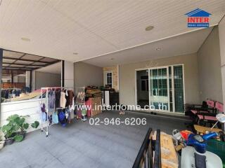 Covered outdoor area of a building with laundry, plants, and a sliding patio door