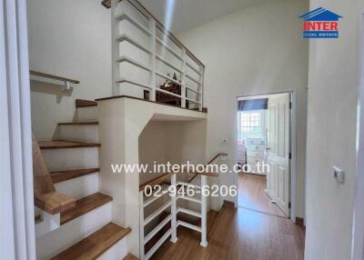 Staircase area with wooden steps and white railings leading to upper floor