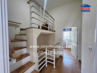 Staircase area with wooden steps and white railings leading to upper floor