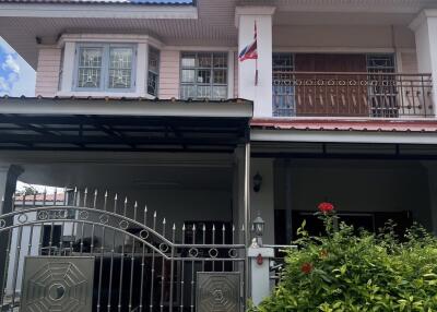 Front view of a two-story house with a gate and a small garden