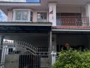 Front view of a two-story house with a gate and a small garden