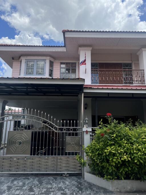 Front view of a two-story house with a gate and a small garden