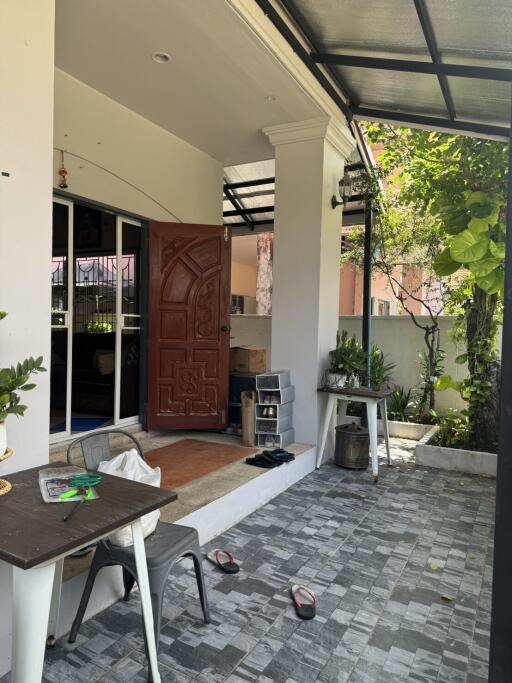 Covered outdoor patio with plants and furniture