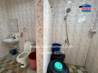 A clean and tiled bathroom with modern fixtures, showerhead, toilet, and sink.