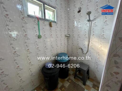 Bathroom with shower area, small window, and toiletries