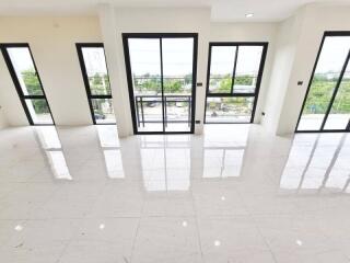 Bright and spacious living area with large windows and white tiled floor