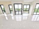 Bright and spacious living area with large windows and white tiled floor