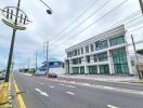 Exterior view of a commercial building with glass windows along a main road