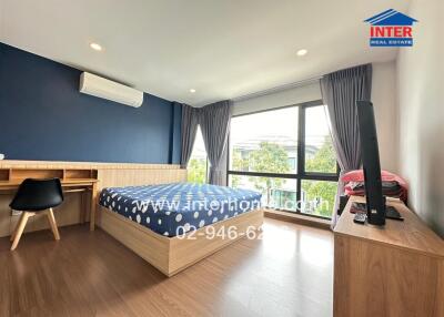 Spacious bedroom with large window, wooden floors, and modern furnishings